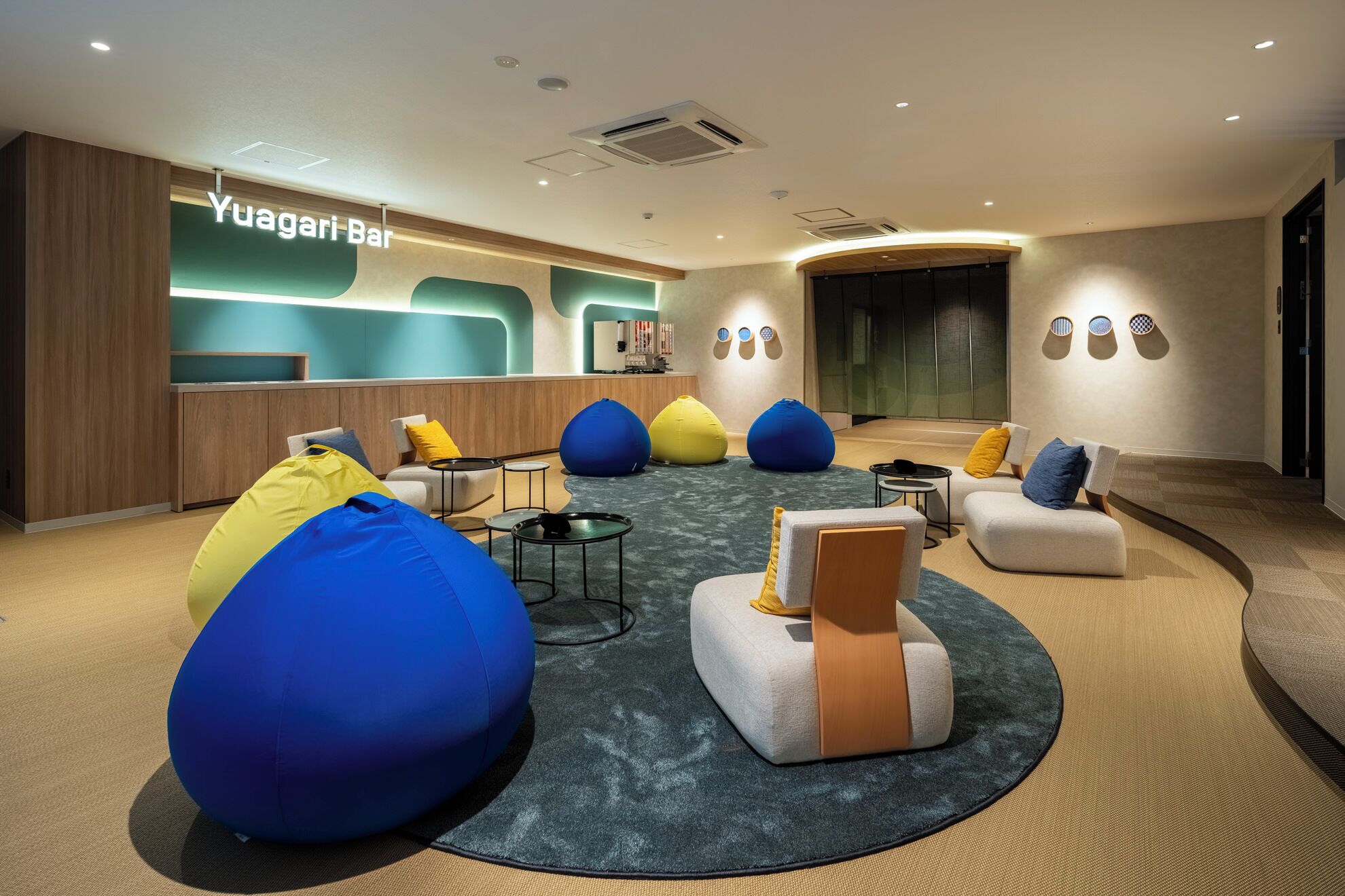 A modern lounge area with seating, a reception desk, and a bar named Yuagari Bar.