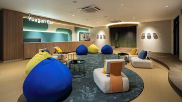 A modern lounge area with seating, a reception desk, and a bar named Yuagari Bar.