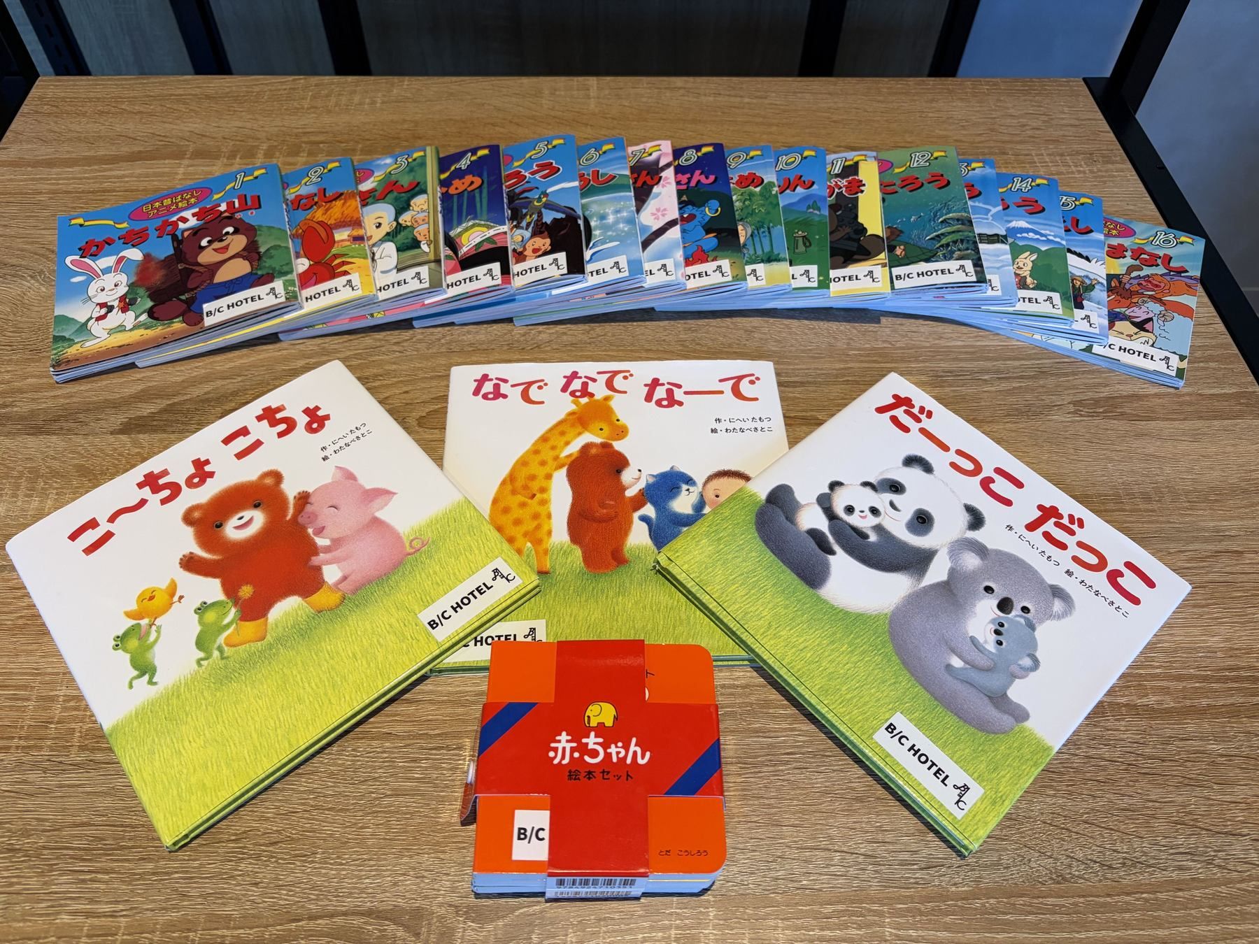 A collection of Japanese children's books with cartoon characters on the cover, arranged on a wooden table.