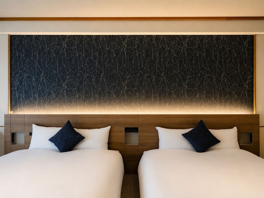 Habitación de hotel con dos camas, una obra de arte grande en la pared y cabecera de madera.