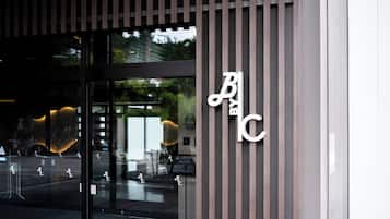 A building entrance with a glass door, vertical wooden slats, and a sign with stylized lettering.
