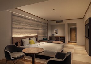 A modern hotel room with a large bed, two armchairs, a small round table, a desk with a chair, a TV, and a large abstract wall mural. - B/C HOTEL KUSATSU (Kusatsu)