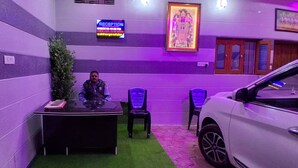A reception area with a reception desk, chairs, a car, and a neon sign. - Gopalkunj Homestay (Faizabad)