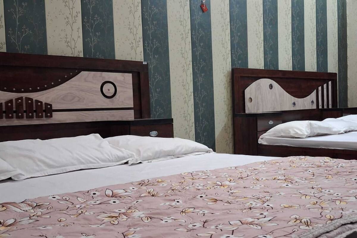 Una habitación con dos camas, papel tapiz a rayas y una cortina.