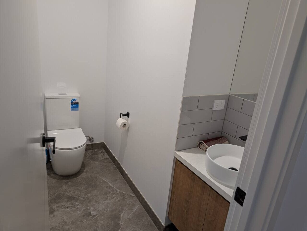 Et lille badeværelse med toilet, toiletpapir og håndvask.