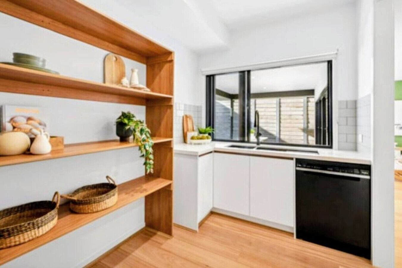 Une cuisine moderne avec des étagères en bois, une fenêtre et un lave-vaisselle.