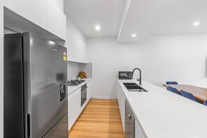 A modern kitchen with a stainless steel refrigerator, a microwave, and a sink. - `Elegant Home in Highton near City` (Highton)