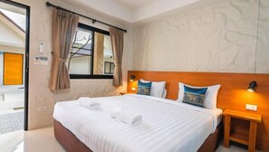 Habitación de hotel con una cama grande, una mesita de noche, una ventana con cortinas y una pared con diseño texturizado.