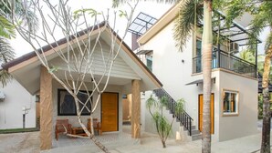 Una casa moderna de dos pisos, con un porche cubierto, una escalera y un balcón.