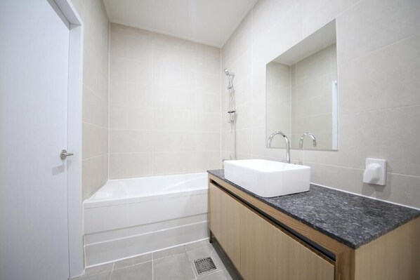 Une salle de bain moderne avec une baignoire, un lavabo et un miroir.