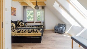 A bedroom with a bed, a window, a hanging light fixture, and a skylight. - Nature experience & close to the city of Berlin: "THE WELSH HOUSE" (No. 56a) (Schönwalde-Glien)