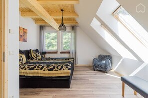 A bedroom with a bed, a window, a hanging light fixture, and a skylight. - Nature experience & close to the city of Berlin: "THE WELSH HOUSE" (No. 56a) (Schönwalde-Glien)