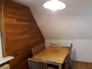 Ein Essbereich mit Holztisch und Stühlen, einem Korb und einer Zeitschrift auf dem Tisch.