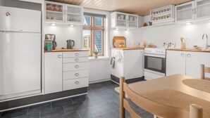 A modern kitchen with white cabinets, a wooden countertop, a built-in oven, and a window with a view of the outside. - 4 Star Holiday Home in Lokken (Lokken)