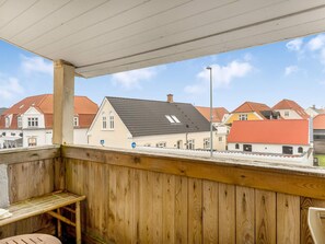 A wooden balcony with a view of houses and a street. - 4 Star Holiday Home in Lokken (Lokken)