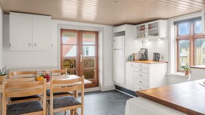 A kitchen with white cabinets, a wooden ceiling, and a dining area with a table and chairs. - 4 Star Holiday Home in Lokken (Lokken)