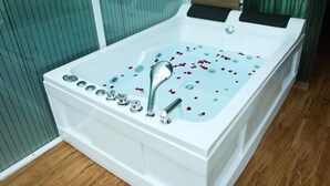 A white bathtub with rose petals, a showerhead, and a control panel. - Hotel Bella Vista (Anuradhapura)