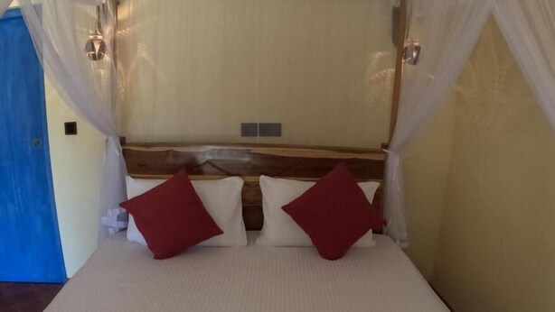 A bed with a canopy, two pillows, and a red bedspread. - Hotel Bella Vista (Anuradhapura)