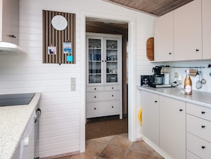A kitchen with white cabinets, a coffee machine, and a wine bottle. - 4 Star Holiday Home in Hejls (Hejls)