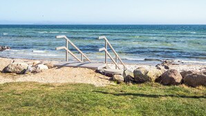 A beach with a wooden structure, possibly a lifeguard stand, and a rocky shoreline. - 4 Star Holiday Home in Hejls (Hejls)