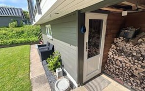 A residential building with a front door, a small garden area with a bench, and a stack of firewood. - 4 Star Holiday Home in Hejls (Hejls)