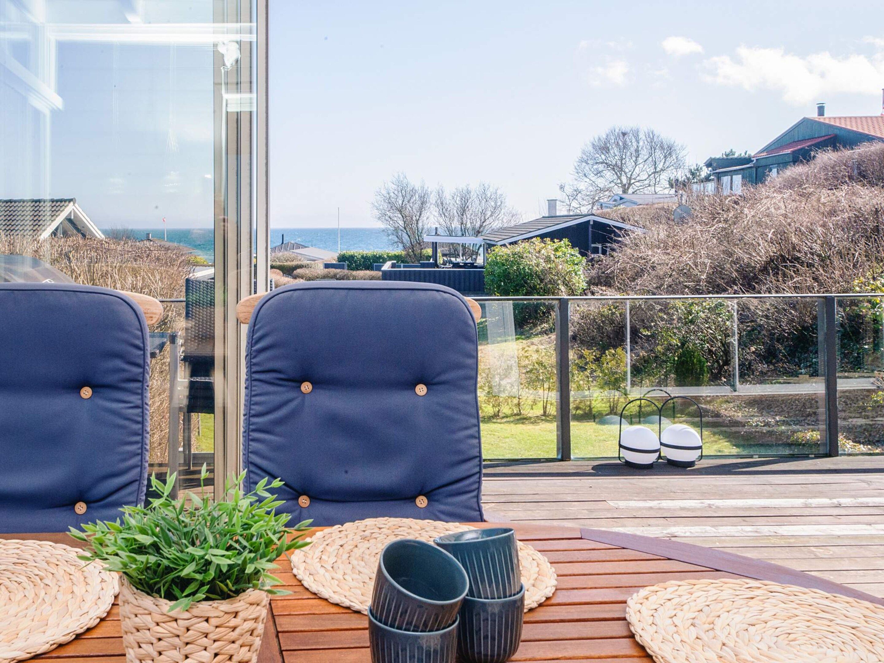 Eine Terrasse mit zwei Stühlen, einem Tisch und Blick auf das Meer und Häuser.