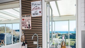A kitchen with a stainless steel sink, wine bottles, and a sign that reads 'All you need is love... and wine.' - 4 Star Holiday Home in Hejls (Hejls)
