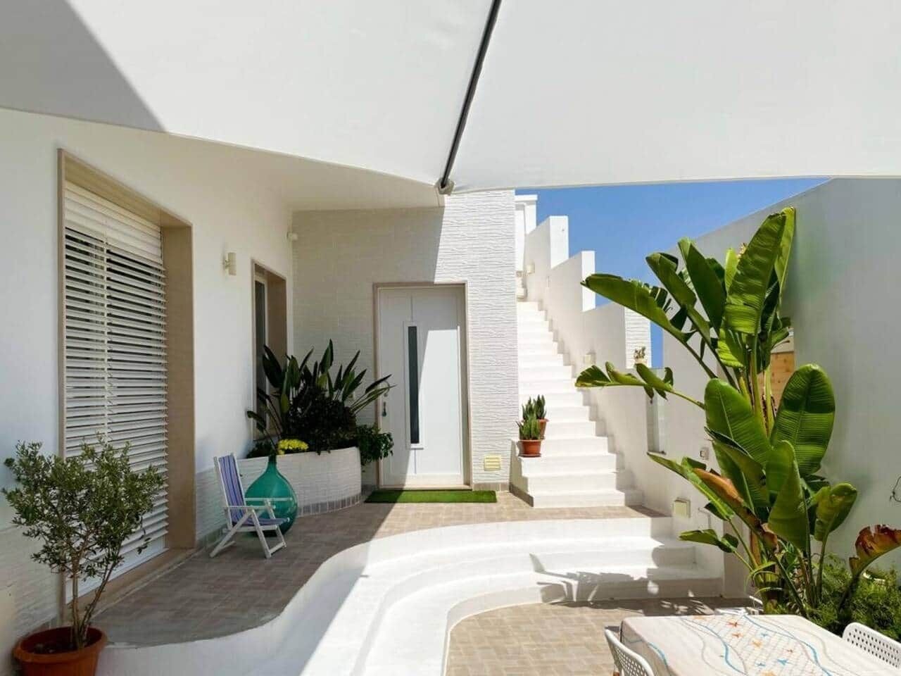 Un espace extérieur moderne avec un escalier blanc, des plantes en pot et une porte.