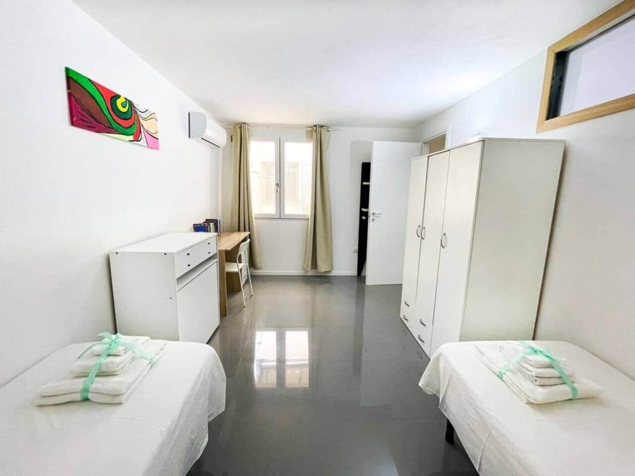 Ett hotellrum med två sängar, ett skrivbord, en garderob och en tavla på väggen.