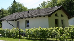 Einbungalow mit Ziegeldach, einer kleinen Veranda und einem Vorgarten.