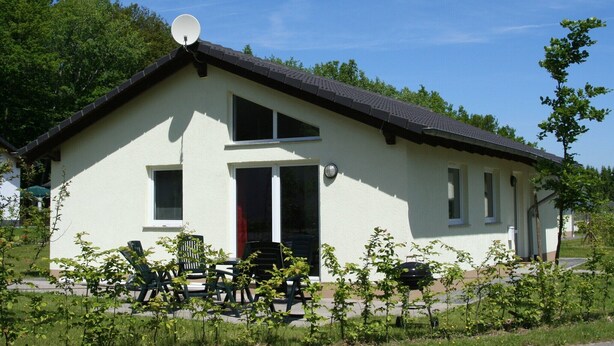 Un bâtiment d’un seul étage, doté d’un toit en pente, d’une antenne parabolique et d’une porte dont le cadre est rouge.