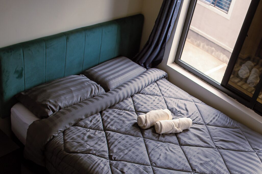Un lit avec une couverture matelassée, des oreillers et une serviette enroulée.