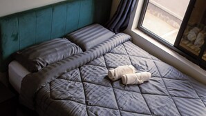 Un lit avec une couverture matelassée, des oreillers et une serviette enroulée.