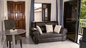 Un salon avec un canapé, une petite table ronde et une porte.