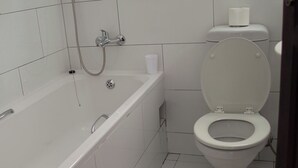 Une salle de bain avec une baignoire blanche, des toilettes et une douche.