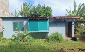 A small, single-story building with a blue exterior, a window with a wooden frame, and a door.