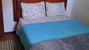 Un lit avec une tête de lit à motifs, une couvre-lit bleue et une couverture grise.