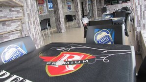 Un restaurant dont l’intérieur est décoré de murs en pierre, avec des tables portant le logo de la bière Castle K Stout, et un espace bar.