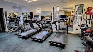 Une salle de sport équipée de tapis de course, de vélos d’exercice et d’appareils de musculation.