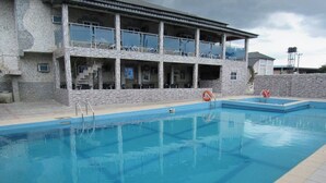 Une piscine avec, en arrière-plan, un bâtiment à la façade en pierre.