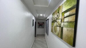 Un couloir doté d’un sol carrelé, de murs blancs et d’un grand tableau abstrait sur le mur de droite.