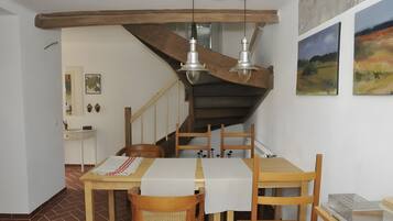 Un comedor con una mesa de madera, sillas y una escalera con barandilla de madera.