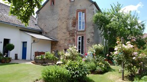 A two-story stone house with a blue door, a small balcony, and a garden with various plants and flowers. - Holiday Home for 4 People (150 m²) in Dodenburg (Dodenburg)