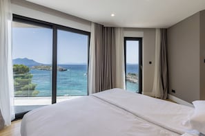 A bedroom with a large bed, a sliding glass door leading to a balcony with a sea view. - Villas Mare & Luce (Pijavičino)