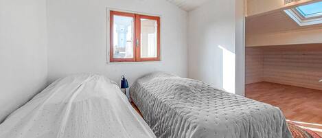 A bedroom with two beds, a skylight, and a view of the outside.