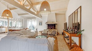 Ein geräumiges Wohnzimmer mit Kamin, einem Essbereich und einer durchgehenden Tür erkennbaren Küche.