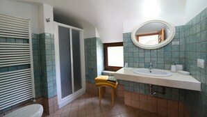 Ein Badezimmer mit Toilette, Waschbecken mit Spiegel und Duschbereich.