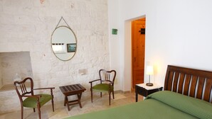 A room with a bed, two chairs, a small table, a mirror, and a lamp. - Room 'Corte Del Camedrio Lamia 2' with Shared Terrace, Wi-Fi and Air Conditioning (Ostuni)
