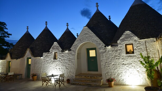 A row of white stone buildings with conical roofs, a green door, and a small window. - Room 'Corte Del Camedrio Lamia 2' with Shared Terrace, Wi-Fi and Air Conditioning (Ostuni)