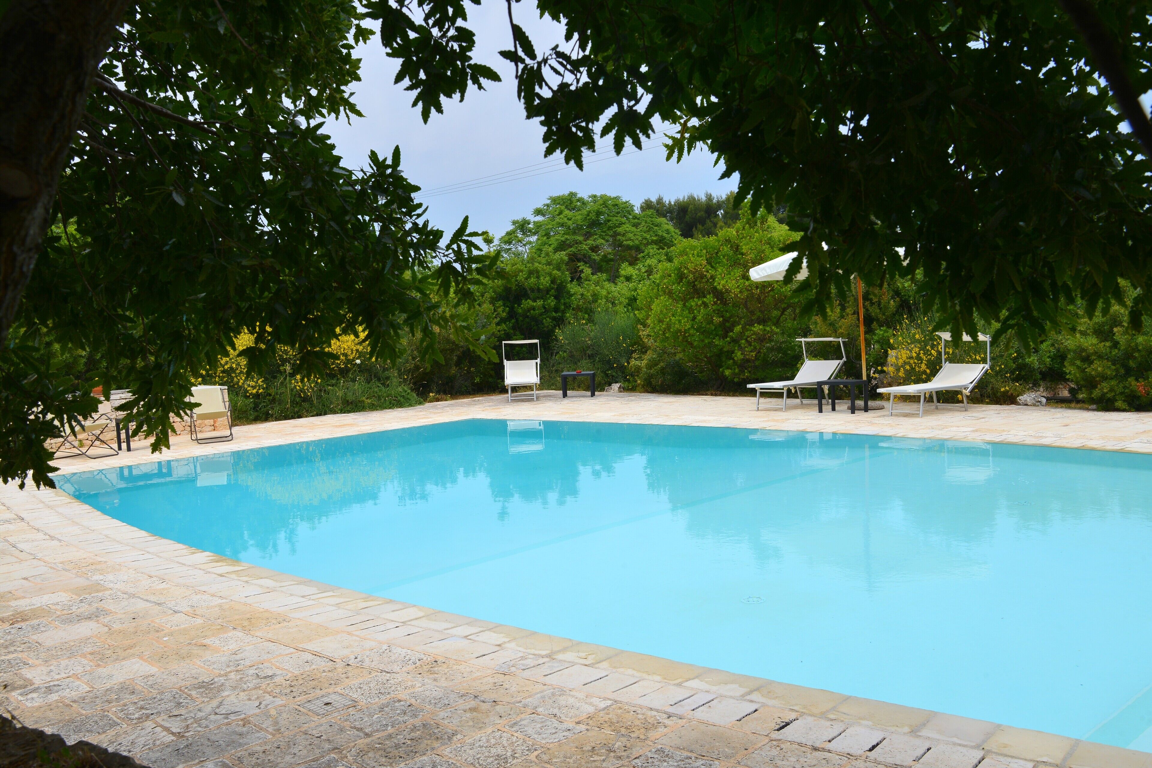 Une piscine dotée de chaises longues et bordée de pierres.